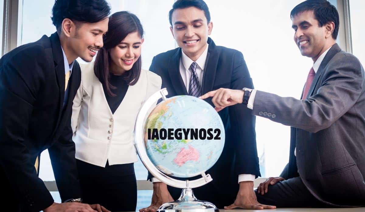 “Group of business professionals in formal attire smiling and pointing at a globe with the text About IAOEGYNOS2 displayed on it.”
